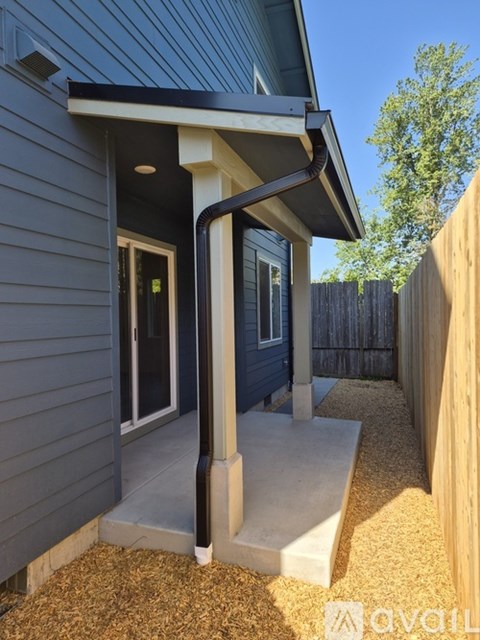 A house with a grey exterior and a black roof with a white door and window.