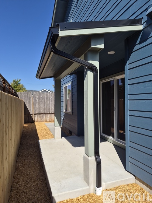A modern house with a blue exterior and a covered walkway.