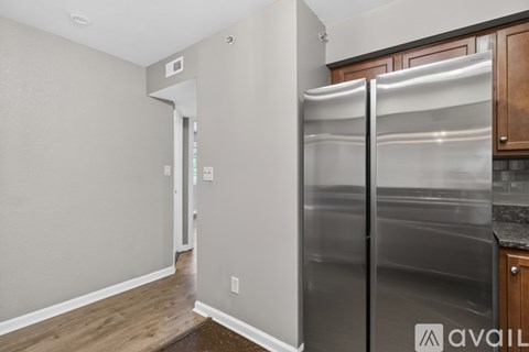 A kitchen with a stainless steel refrigerator and wooden cabinets.