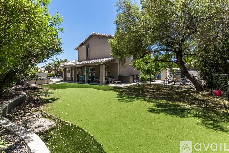 A house with a green lawn and trees in front of it.