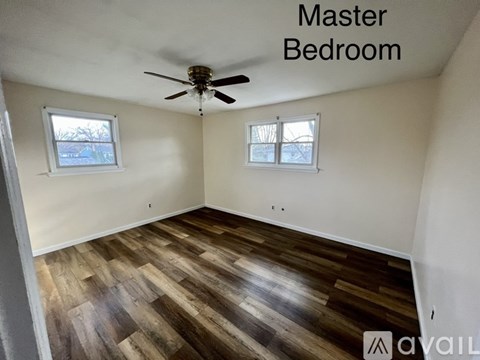 A master bedroom with wood flooring and a ceiling fan.
