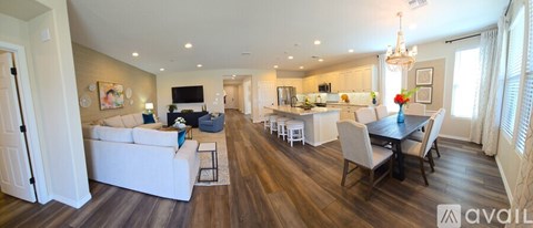 A spacious living room with a white couch and a dining table set up.