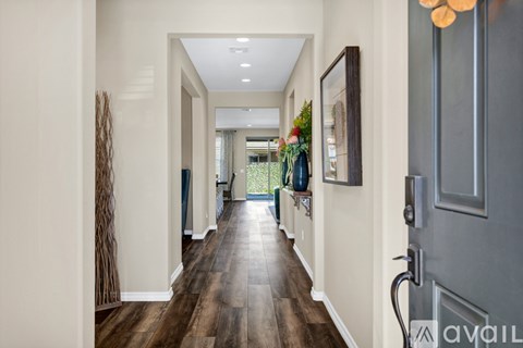 A long hallway with wood floors and white walls.