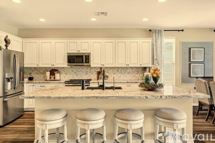 A kitchen with white cabinets and a marble countertop.