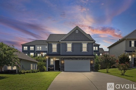 A modern house with a large front yard and a driveway.
