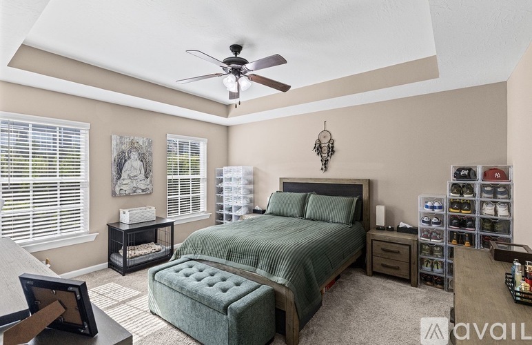 A bedroom with a bed, nightstand, and a fan.