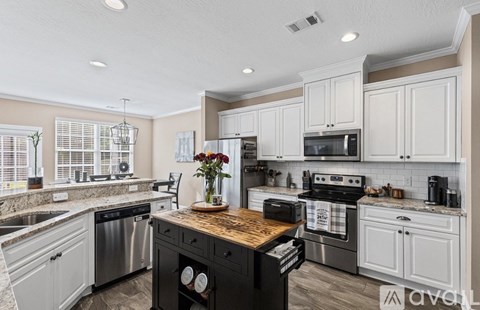 A kitchen with a black stove top oven and white cabinets.