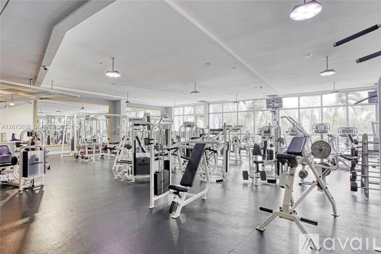 A gym with various exercise equipment and a large mirror on the wall.