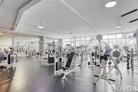 A gym with various exercise equipment and a large mirror on the wall.