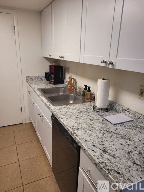 A kitchen with white cabinets and a granite countertop.