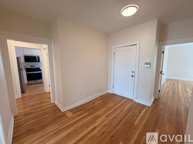 A room with wooden floors and white walls, with a door on the right side.