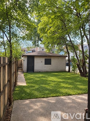 A small house with a black door is surrounded by a green lawn and trees.