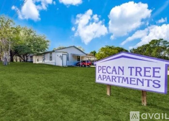 A sign for Pecan Tree Apartments is displayed in front of a building.