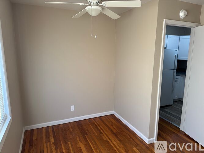 A room with a ceiling fan and wooden flooring.