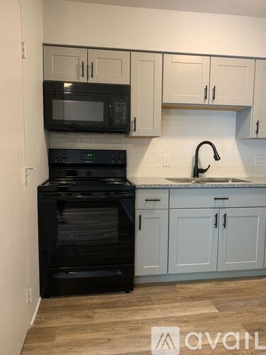 A kitchen with black appliances and white cabinets.
