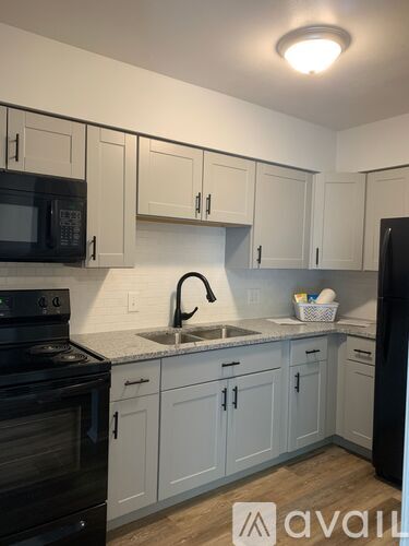 A kitchen with white cabinets and black appliances.