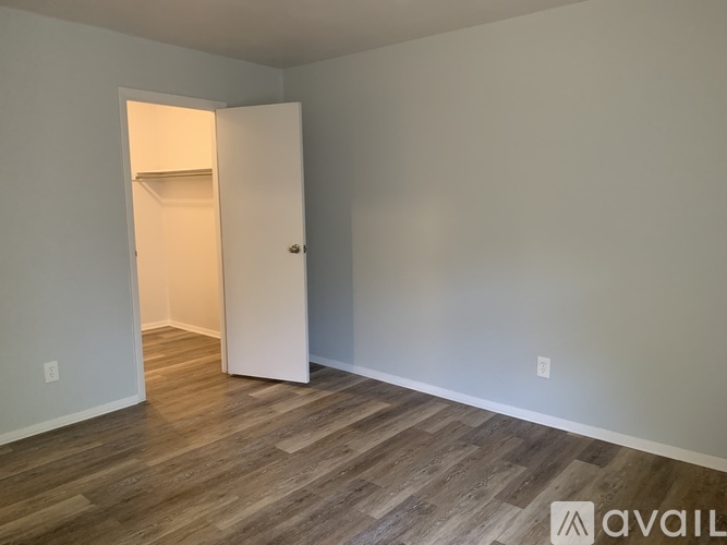 A room with a white door and wooden flooring.