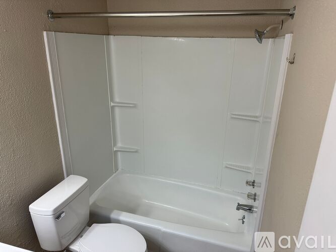 A white toilet sits next to a white bathtub in a bathroom.