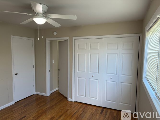 A room with a ceiling fan and wooden floors.