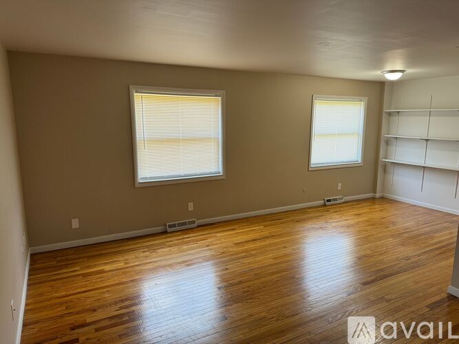 Empty room with wooden floors and two windows.