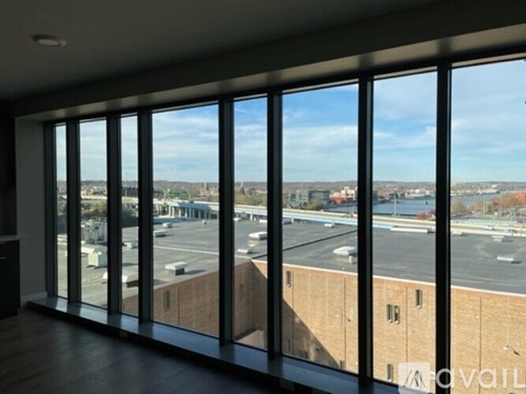 A room with a view of a parking lot and buildings outside.