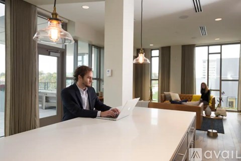 A man in a suit is working on a laptop in a bright, modern office space.