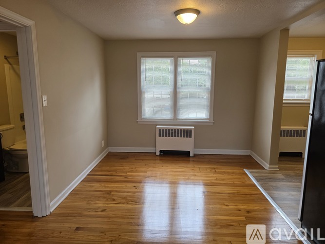 A room with wooden floors and a window with blinds.