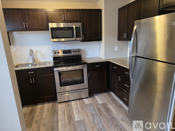 A kitchen with a stainless steel refrigerator, microwave, oven, and sink.