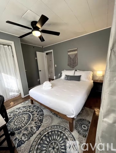 A bedroom with a white bed and a ceiling fan.