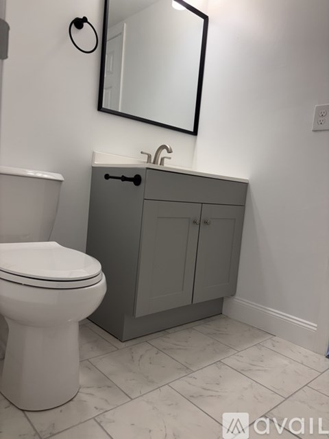 A white toilet sits next to a gray cabinet in a bathroom.