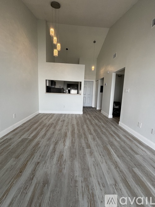 A spacious room with wooden flooring and a light fixture hanging from the ceiling.