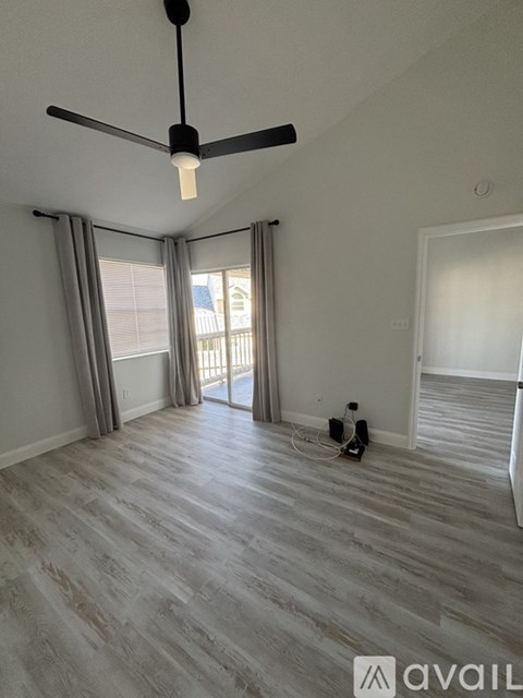 A spacious room with wooden flooring and a light fixture hanging from the ceiling.