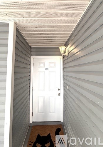 A cat is sitting on a doormat in front of a white door.