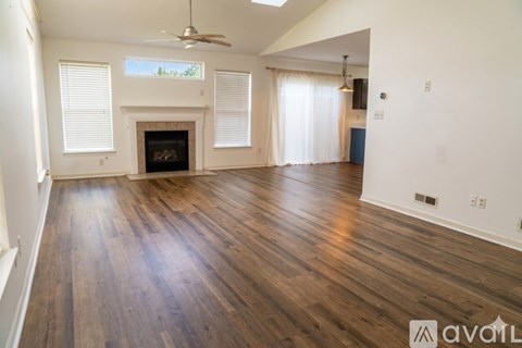 A spacious living room with wood flooring and a fireplace.