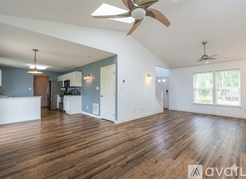 A spacious room with wooden floors and a ceiling fan.