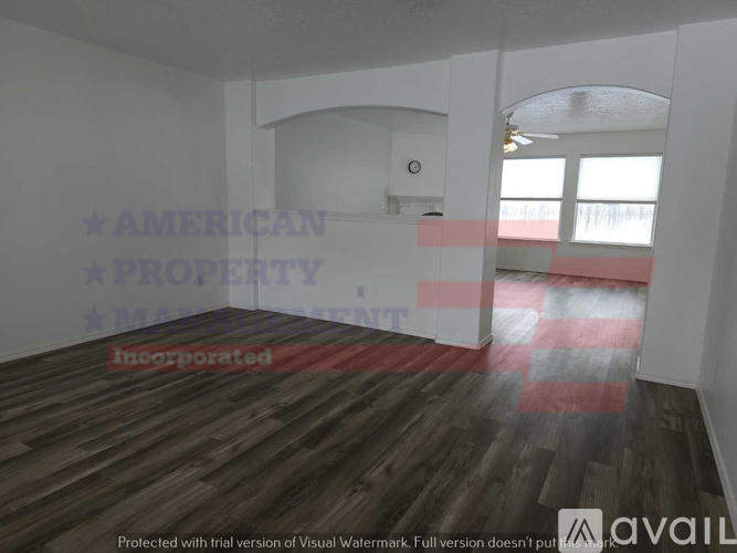 A room with wooden flooring and white walls, with a window on the right side.
