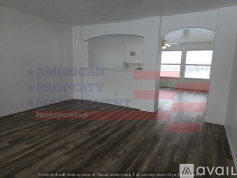 A room with wooden flooring and white walls, with a window on the right side.