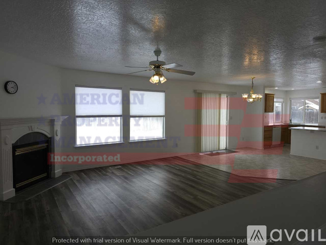 A spacious room with a fireplace and a ceiling fan.