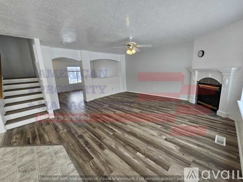 A living room with wooden flooring and a staircase.