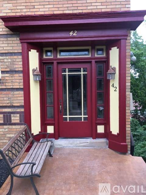 A red door with a glass window and a bench in front of it.