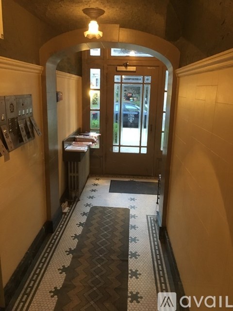 A hallway with a tiled floor and a door at the end.