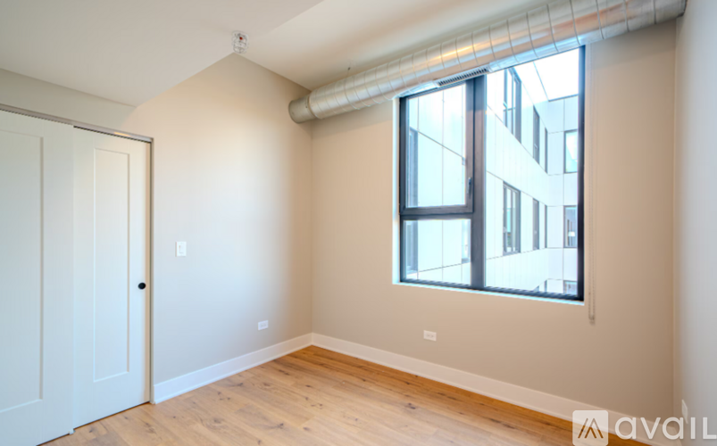 A room with a white door and a window with a view of a building outside.