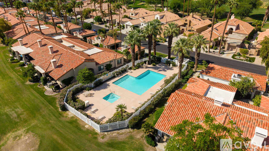 A swimming pool surrounded by houses and palm trees.