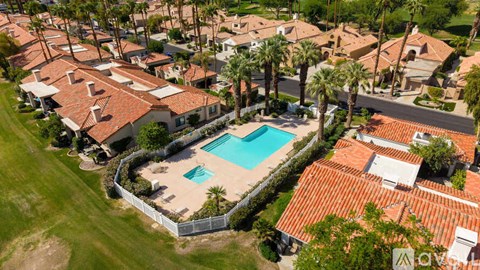 A swimming pool surrounded by houses and palm trees.