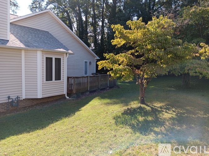 A house with a white siding and a tree with yellow leaves in front of it.