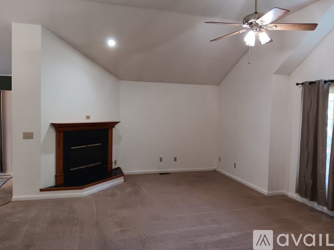 A spacious room with a fireplace and a ceiling fan.