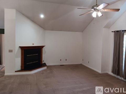 A spacious room with a fireplace and a ceiling fan.