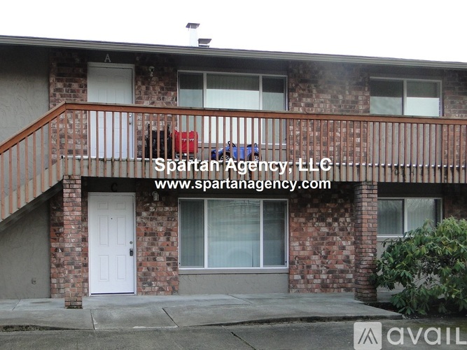 A brick house with a balcony and a sign that says "Spartan Agency, LLC".