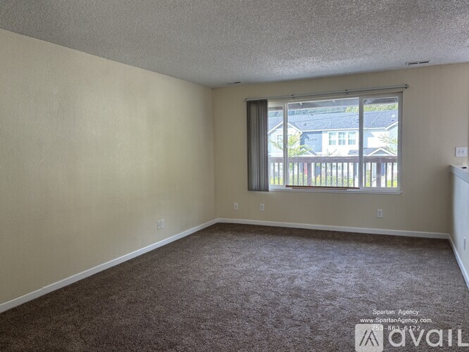A room with a carpeted floor and a window with a view of a deck.