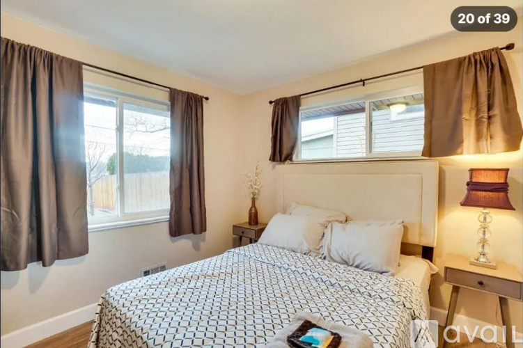 A bedroom with a large bed and a window with curtains.